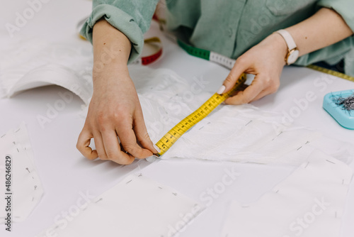 Tailor working process, taking measurements of pattern for new dress.