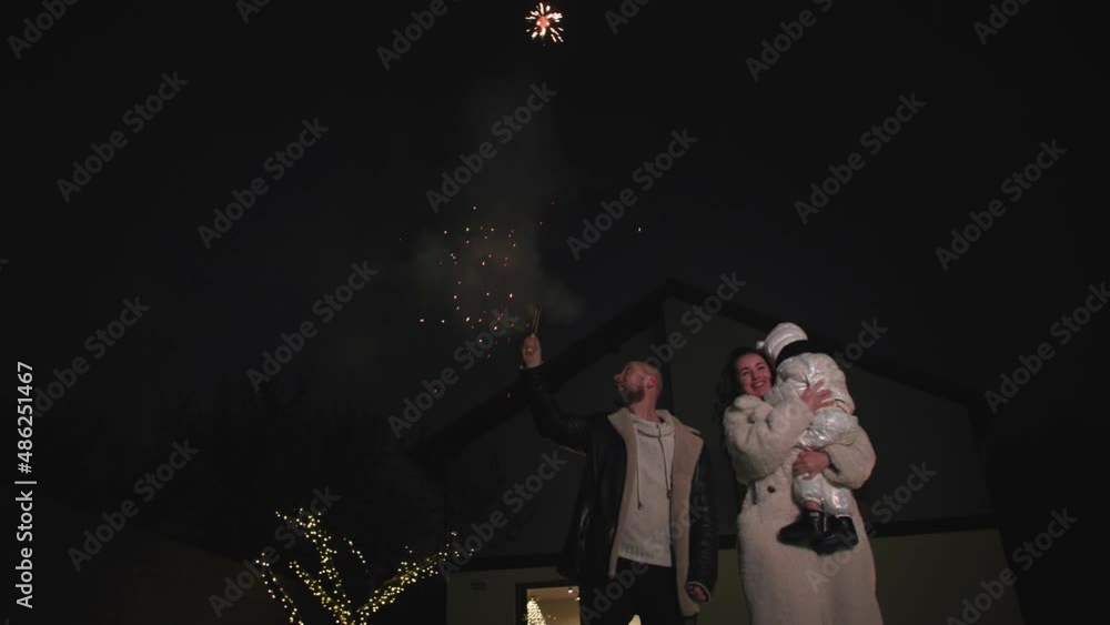 family party, woman and man with their children have fun launching fireworks against the backdrop of a house with bright lights in the late evening family party, woman and man with their children have fun launching fireworks against the backdrop of a house with bright lights in the late evening