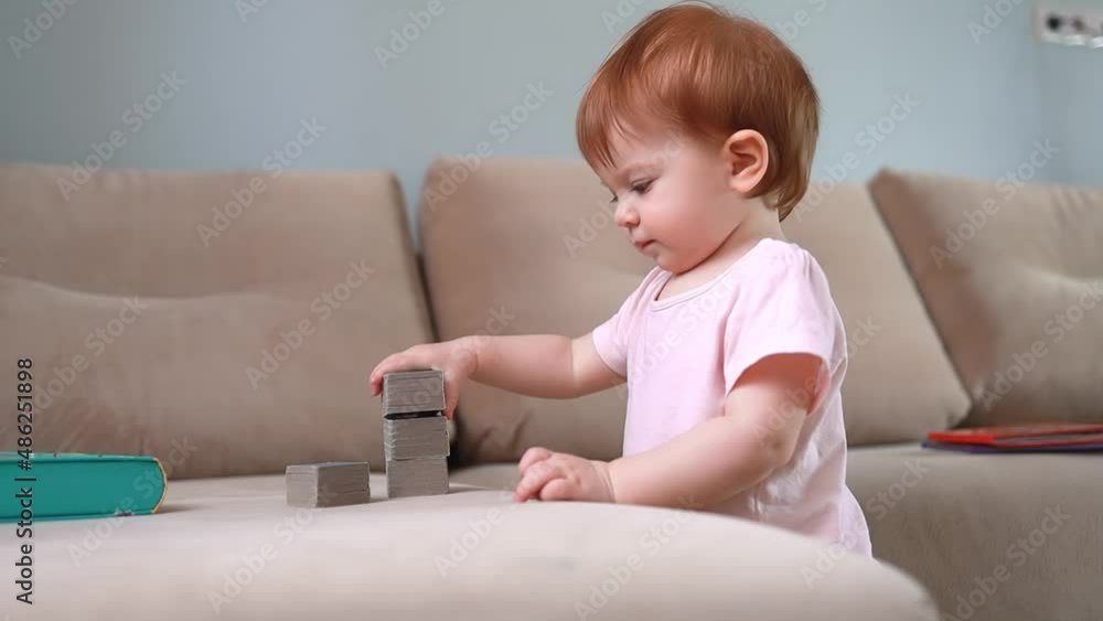 cute toddler plays assembles a tower of cube books and claps hands, concept development of children. cute toddler plays assembles a tower of cube books and claps hands, concept development of children.