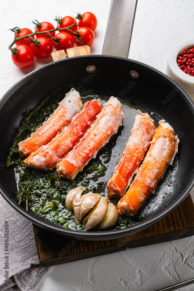 Cooked Organic Alaskan King Crab Legs with Butter, in cast iron frying pan, on white stone table background