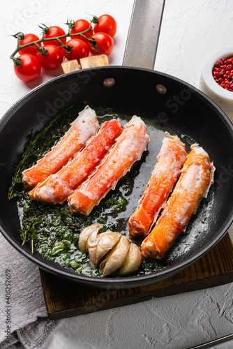 Cooked Organic Alaskan King Crab Legs with Butter, in cast iron frying pan, on white stone table background