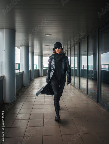 Stylish girl in black coat on roof of business center in form of an agent and spy © okostia