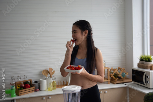 young Asian woman cooking vegetable healthy food and eating or drinking in home kitchen