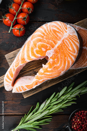 Fesh raw salmon fillet with herbs, on old wooden table, top view