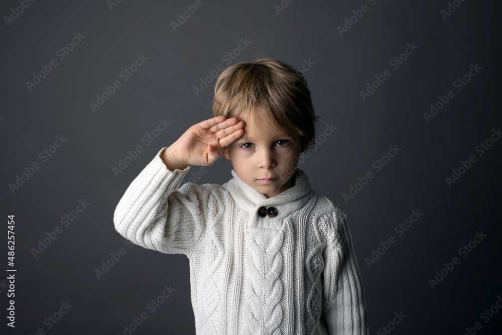 Cute little toddler boy, showing HELLO gesture in sign language on gray background, isolated image, child showing hand sings