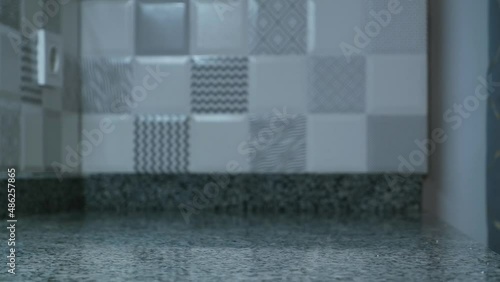 a man's hand raises a glass of cool water. A half-drunk cup of water on the kitchen table.