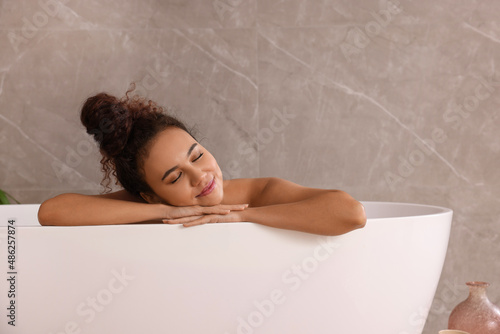 Beautiful African American woman taking bath indoors