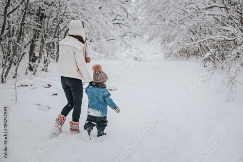 Mom and son are walking in the snow in the forest.