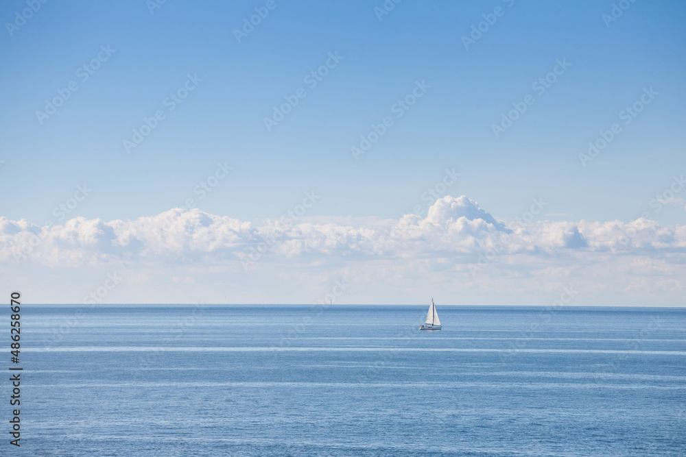 Panorama of the adriatic sea, a blue sea with a sunny blue sky, with a sailboat, a sailing ship passing by over the horizon, during holidays and vacation in summer. ..