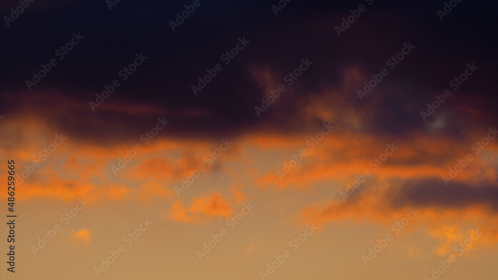 Crépuscule serein, entrecoupé par quelques passages nuageux, sous une lumière orangée