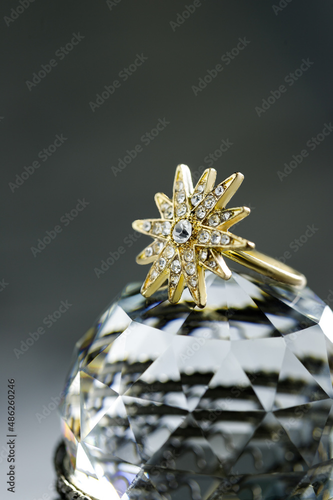 gold ring in the form of a multi-beam star with diamonds lies on a polyhedral crystal, dark background, close-up