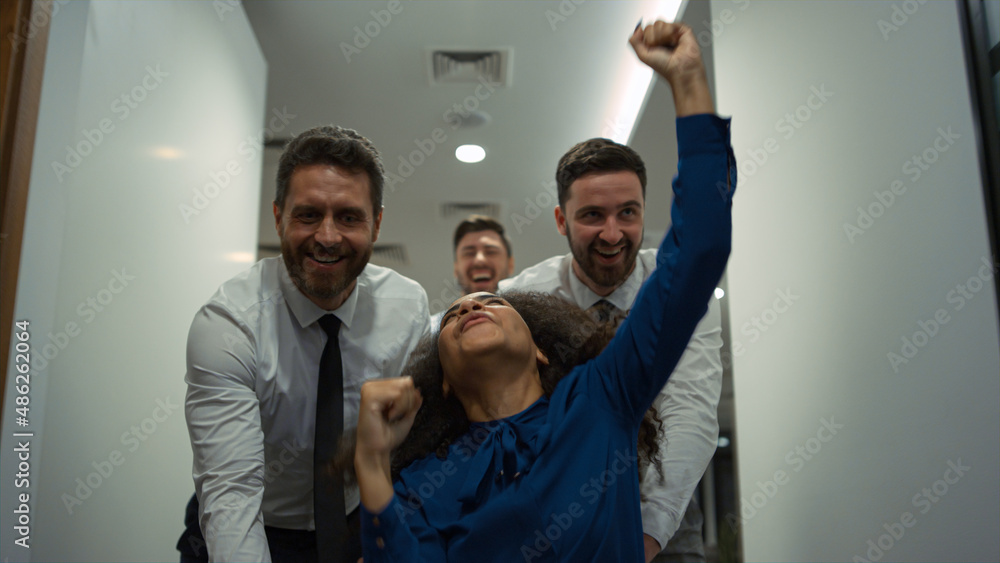 Management team racing chair in office. Multi ethnic colleagues celebrate work. Management team racing chair in office. Multi ethnic colleagues celebrate work.