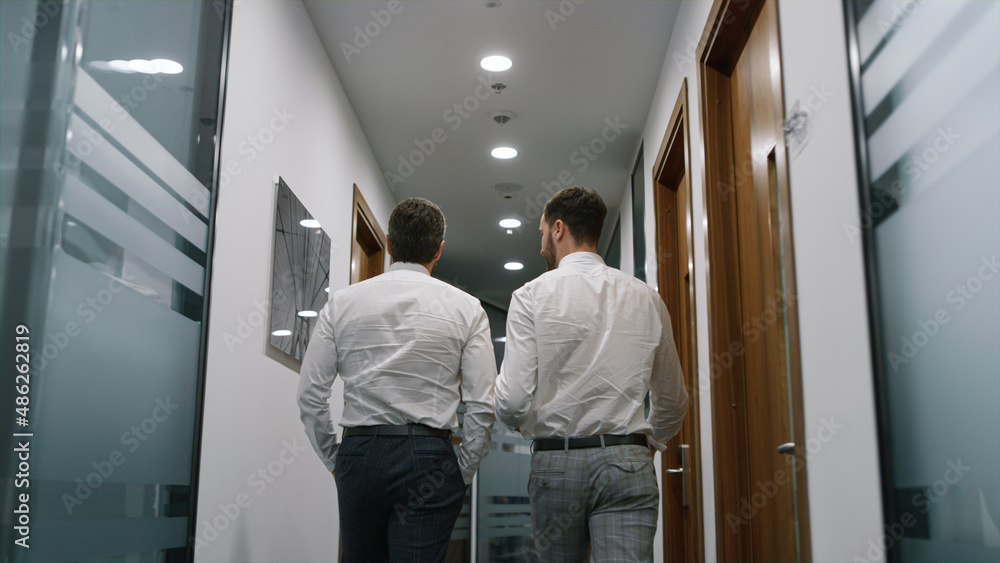 Two businessman walk office discuss corporate data together in finance company. Two businessman walk office discuss corporate data together in finance company.