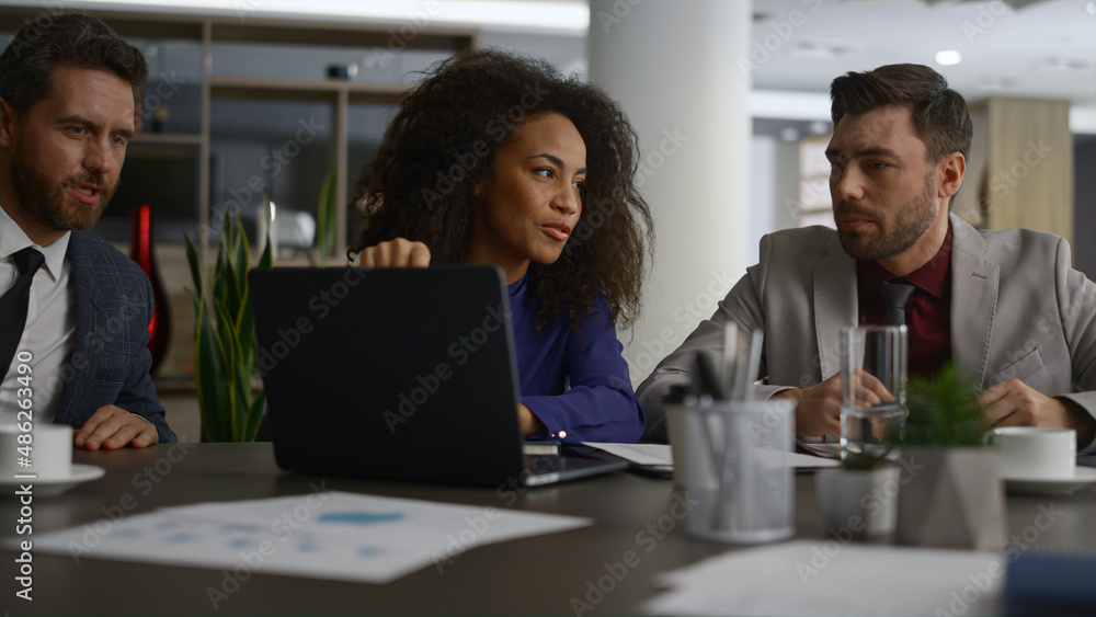 Fototapeta premium Multiracial coworkers talking finance using laptop in modern company office.