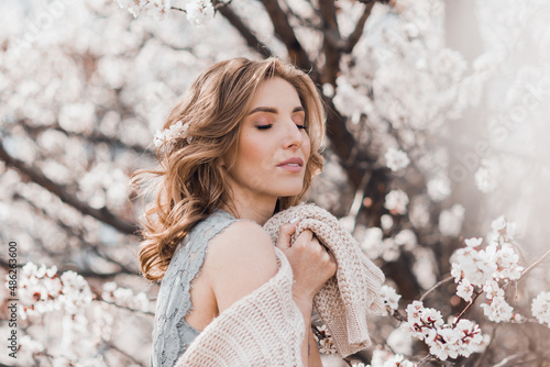 Portrait of pretty blong girl posing against the spring blooming trees in the garden. photo