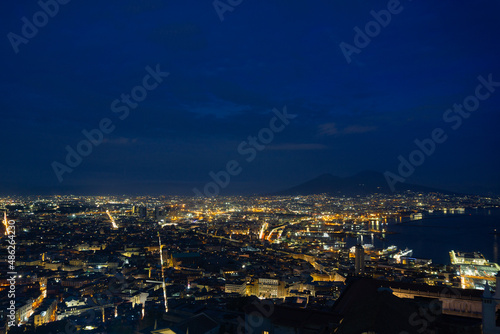 Panoramic view of Naples with Vesuvius in the background  the blue sky with clouds at sunset. City lights on with long exposure.