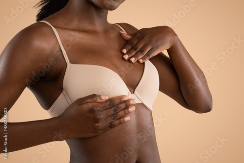 Breast screening concept. Blak lady in bra rubbing her breast photo