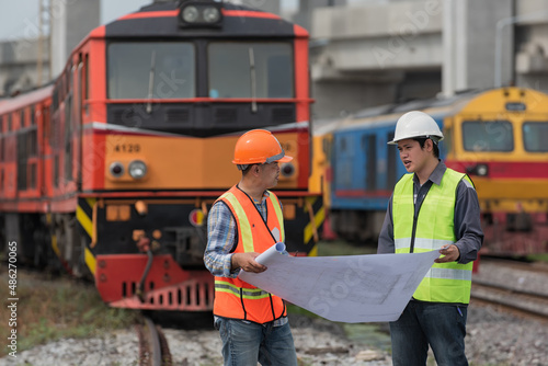 worker and engineer discuss job with locomotive on background. railways, engineer, worker, construction