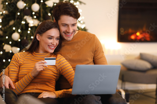 happy couple using pc and debit credit card at home