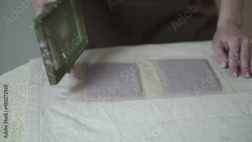 A woman holding a frame for making paper sheets from recycled paper. Selective focus. Household hobby, paper recycling. The concept of zero waste, recycling, ecology