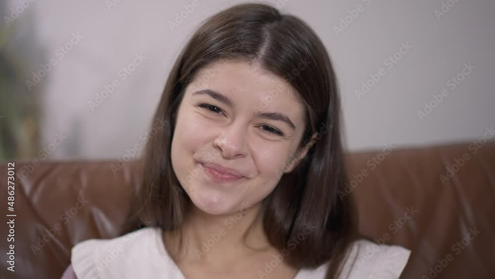 Headshot portrait of young charming Caucasian woman looking at camera with toothy smile indoors. Close-up smiling face of beautiful confident millennial lady posing Headshot portrait of young charming Caucasian woman looking at camera with toothy smile indoors. Close-up smiling face of beautiful confident millennial lady posing
