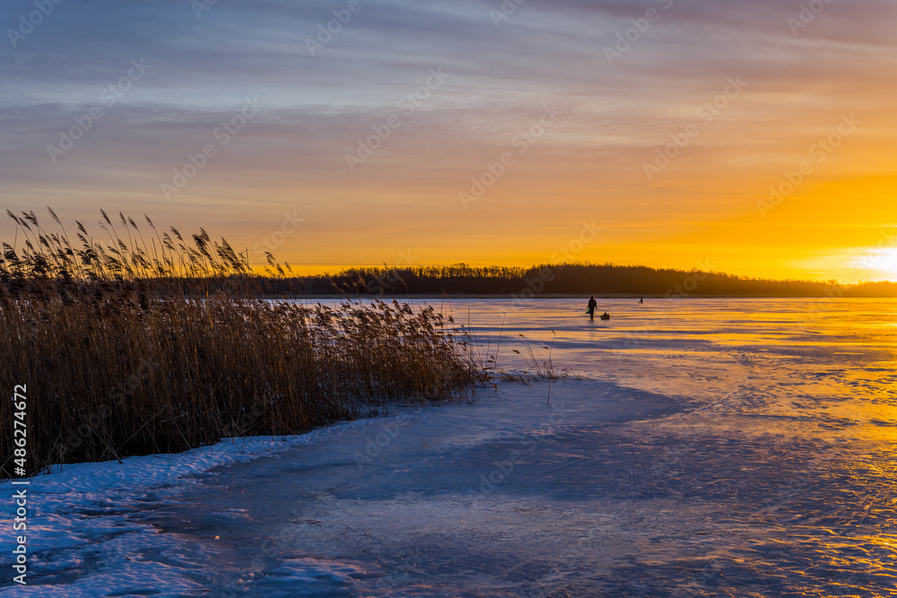 People walking on the stunning frozen Lake Maardu near Tallinn, Estonia at sunrise