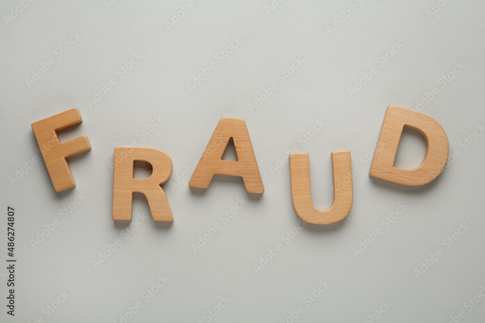 Word Fraud made of wooden letters on grey background, flat lay