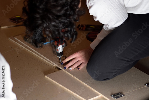 photograph of a young woman who is making DIY using wood at home. selective focus