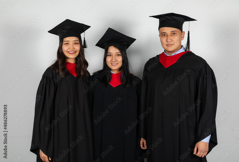 Group of graduate students friends pose together smiling in gowns and capes Group of graduate students friends pose together smiling in gowns and capes