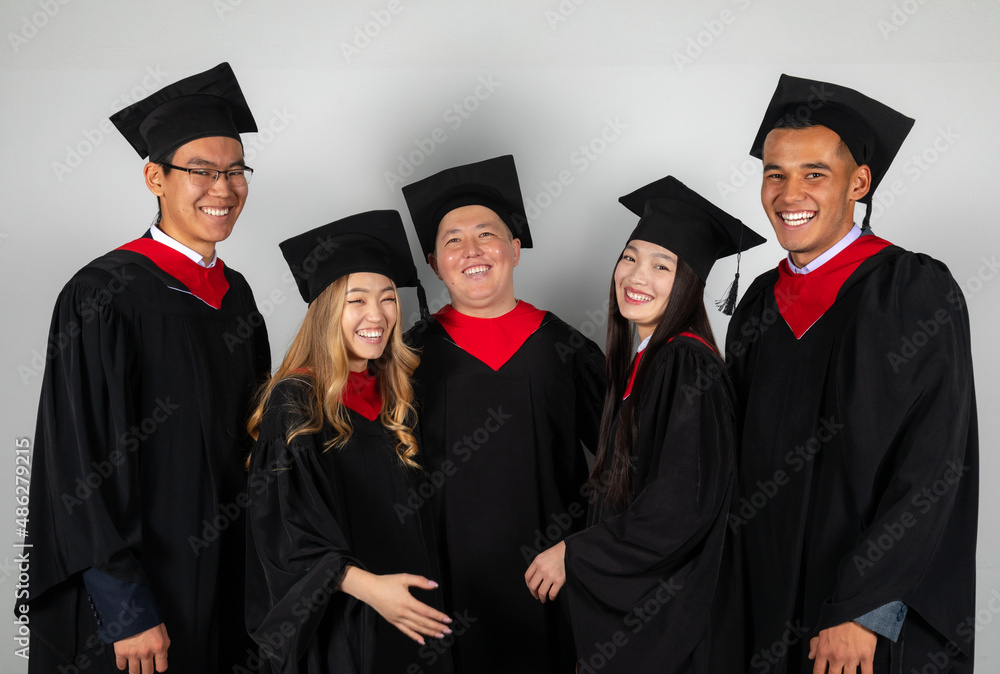 Group of graduate students friends pose together excitedly laughing Group of graduate students friends pose together excitedly laughing