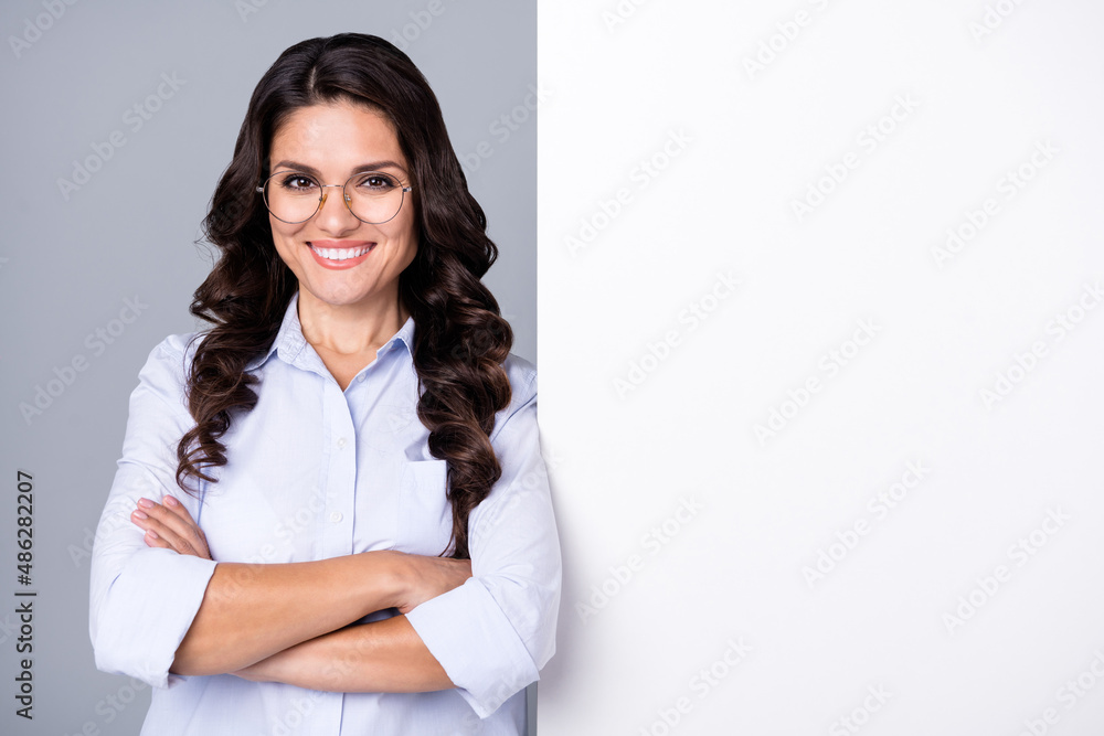Photo of self-assured lady folded arms white placard empty space wear glasses blue shirt isolated grey color background Photo of self-assured lady folded arms white placard empty space wear glasses blue shirt isolated grey color background