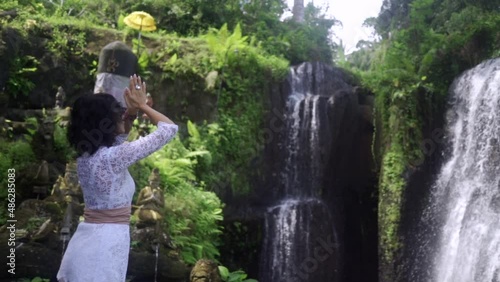 Elegant yoga woman enjoying tranquil nature, feeling the energy of tropical wild waterfall in jungles 