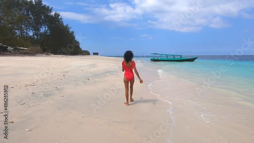 Happy brunette woman walking on the white sand, enjoying summer exotic journey to the ocean coast
