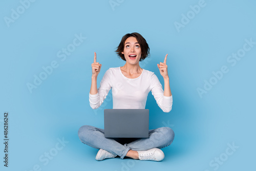 Photo of funny impressed woman wear white shirt legs crossed chatting modern gadget empty space isolated blue color background © deagreez