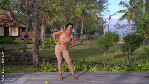 Fitness woman teacher showing exercises for hips and back, sport open-air lessons on the wellness trip