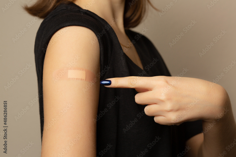 Woman with adhesive plaster on her hand after vaccination