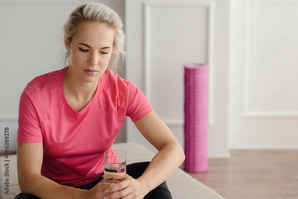Fit beautiful woman in sportswear with glass of water after training Fit beautiful woman in sportswear with glass of water after training