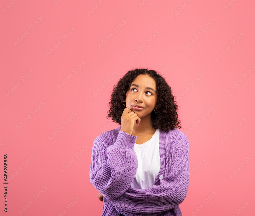 Pensive African American female touching her chin, pondering on offer, feeling doubtful, looking at empty space Pensive African American female touching her chin, pondering on offer, feeling doubtful, looking at empty space