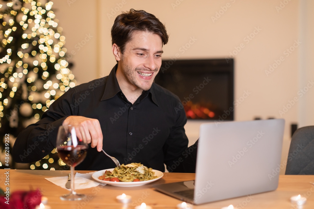 Excited man having dinner during virtual date on laptop Excited man having dinner during virtual date on laptop