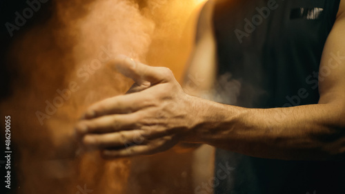 Cropped view of sportsman applying talc on hands on dark background