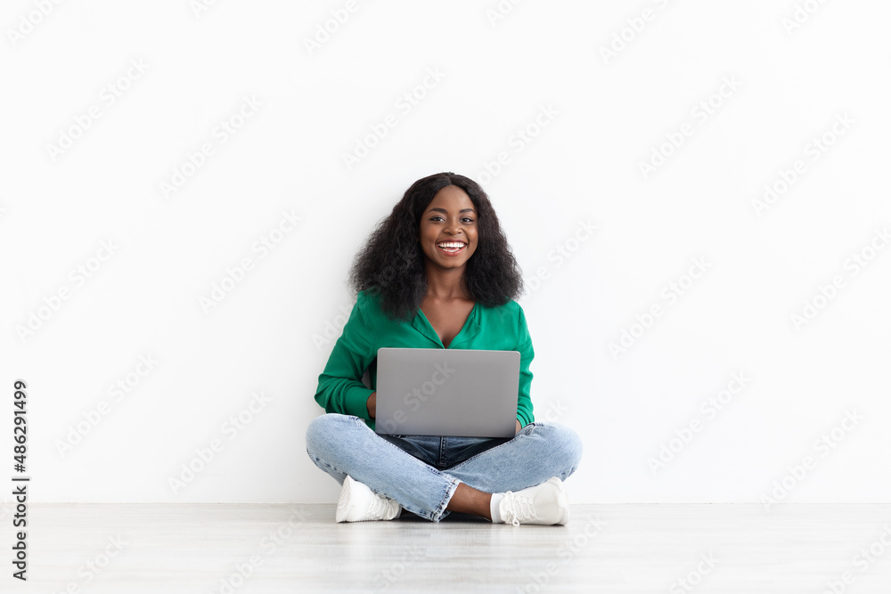 Naklejka premium Smiling pretty african american woman with laptop on white
