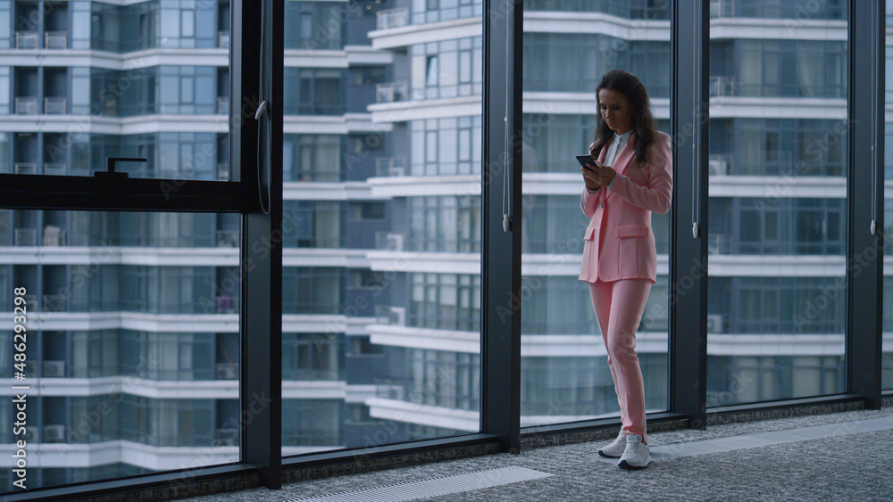 Focused woman texting phone message browsing internet in business office window. Focused woman texting phone message browsing internet in business office window.