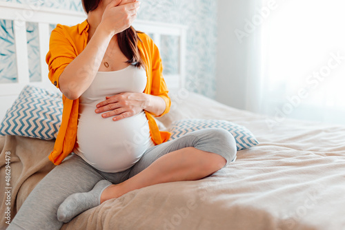 The pregnant girl covers her mouth with her hand. Toxicosis, suffer from vomiting, morning sickness, feel bad during pregnancy.