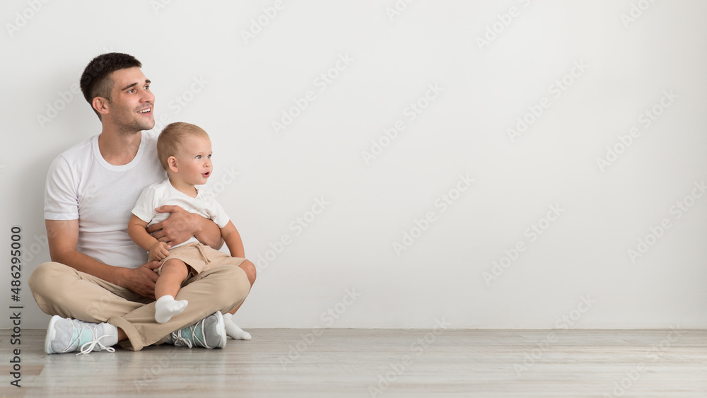 Baby Offer. Father With Infant Child On Arms Looking Aside With Interest Baby Offer. Father With Infant Child On Arms Looking Aside With Interest