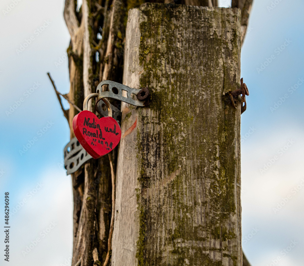 Fototapeta premium Rotes Liebesschloss an einem Holzpfahl