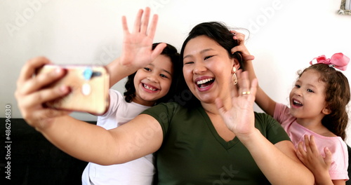 Mother and children blowing kisses on video communication holding cellphone device  family talking to relative