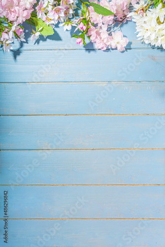 Hello spring concept. Spring holidays greeting card simple flatlay background with artificial blossom spring flowers on light blue wooden garden table background = frame copy space top view