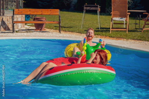 Couple having fun playing with squirt guns at the swimming pool © Impact Photography
