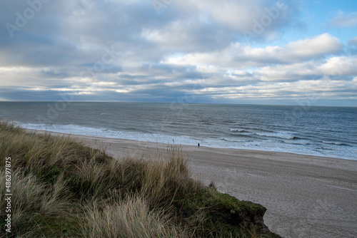 Eine Person steht im Winter am Strand von Kampen Insel Sylt und schaut auf das Meer 