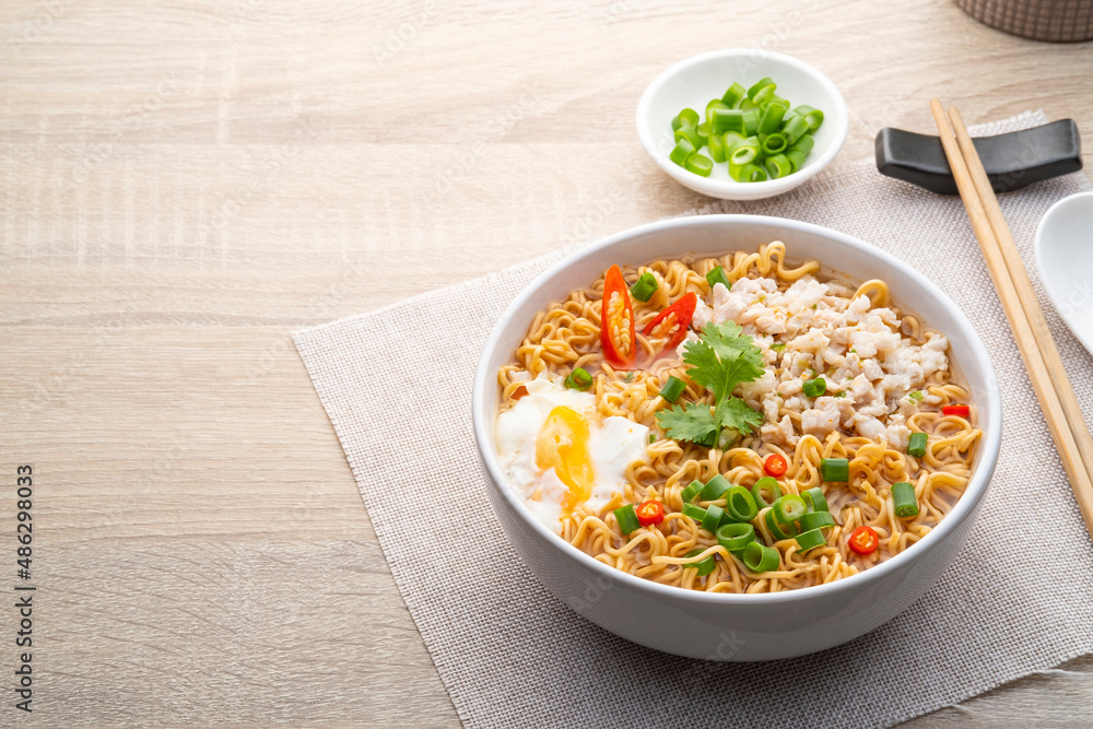 Instant noodle soup with minced pork and boiled egg in white bowl on wood table.with copy space Instant noodle soup with minced pork and boiled egg in white bowl on wood table.with copy space